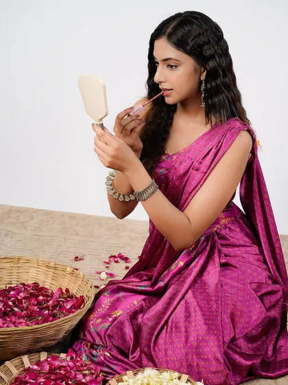 A wider shot from the same beauty campaign, this image sets a scene. The model is surrounded by rose petals, creating a soft and romantic context for the makeup product she is applying.