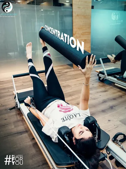 Focus your concentration to channel the benefits of Pilates. This client uses a foam roller on the reformer to challenge her stability while working on leg flexibility.