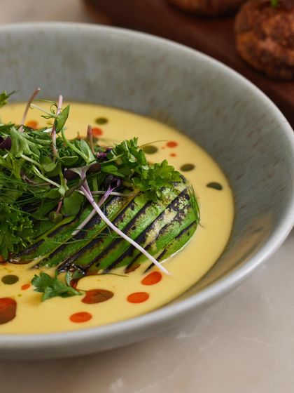A close-up on the details of the Torched Avocado Ceviche, showing the colorful oil droplets and fresh microgreens.