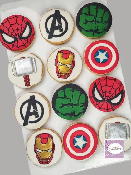 Avengers-themed cookies decorated with royal icing, featuring the logos and symbols of iconic heroes.
