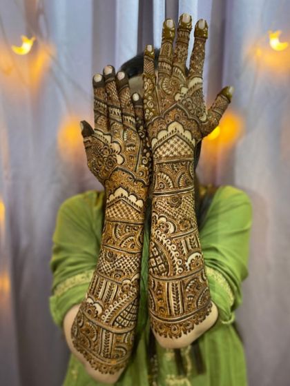 A classic bridal pose, showing off the full extent of the intricate henna work. The symmetry and detail are what make these designs so special.