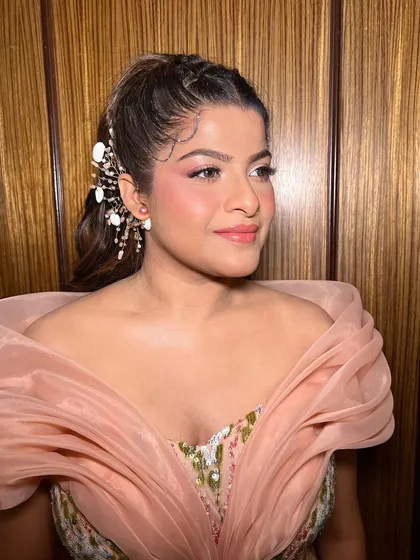 A fun 'coral-pink-me-up' glam look that is both chic and playful. The makeup perfectly complements her unique gown and the celebratory vibe of the event.