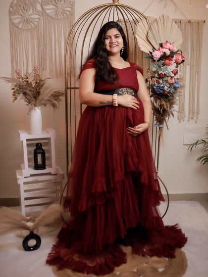 This maroon ruffled gown is perfect for an indoor studio maternity shoot. The rich color and layered tulle create a look of pure elegance.