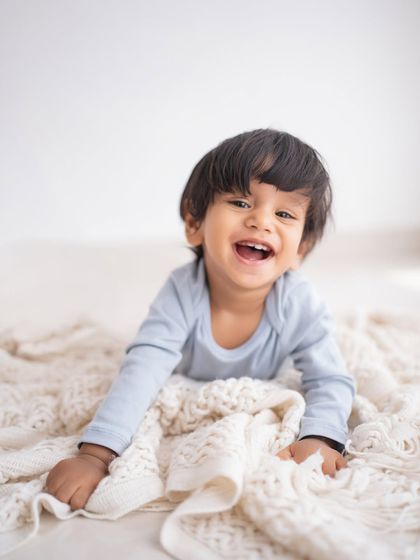 A happy baby boy lying on a soft blanket.