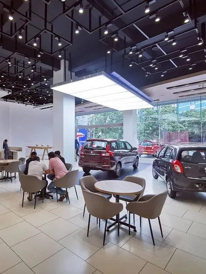 A view of the spacious and modern interior of a redesigned Maruti Suzuki Arena showroom. We focused on creating an open, welcoming environment with clear sightlines to the cars, comfortable customer seating areas, and dynamic ceiling and lighting design to enhance the retail experience.