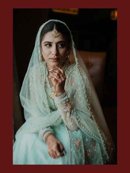 A classic, moody portrait of the bride seated by a window. The natural light beautifully illuminates her features and elegant attire.
