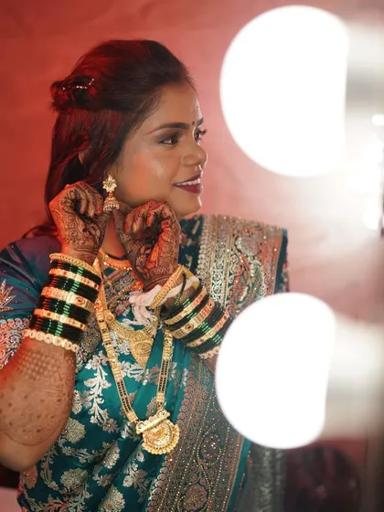 Getting ready for her reception. This artistic shot captures her putting on her earrings, with her flawless makeup and traditional jewelry on full display.