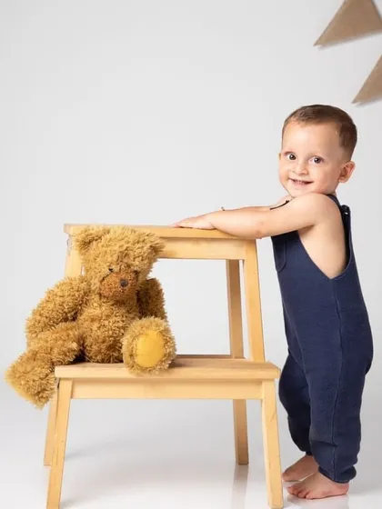 Standing proud with his teddy bear. Using simple props like a stool helps babies who are just learning to stand, resulting in adorable portraits.