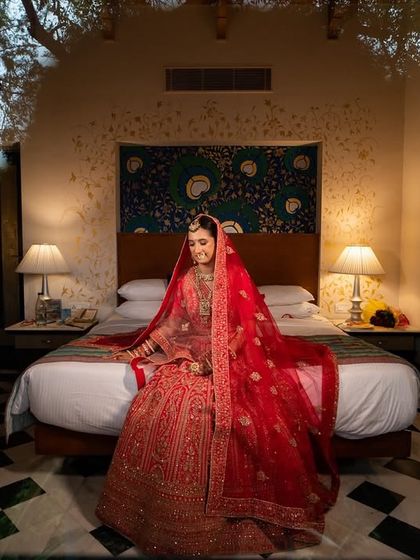 A beautiful bridal portrait, with the bride seated on a bed, framed by the window looking out onto the trees.