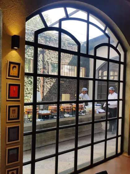 Our chefs at work, seen through the elegant arched windows of a stylish private residence. We can set up our kitchen anywhere, ensuring fresh, high-quality food is prepared on-site for your guests.