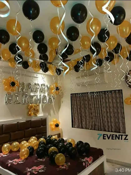 A birthday room surprise with black and gold balloons floating on the ceiling and covering the bed.