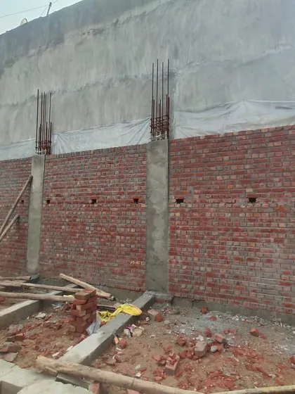 Another angle of the residential construction site. You can see the foundation and plinth beams are complete, and the brick walls are being erected, forming the outline of the new home.