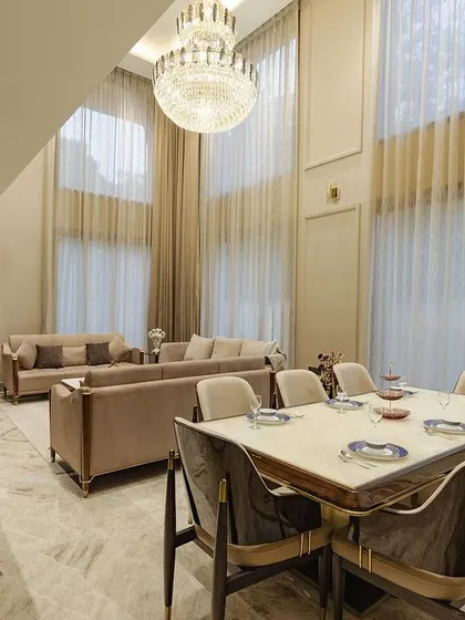 The dining area is seamlessly integrated into the double-height living space. This allows for a cohesive feel while entertaining, with the grandeur of the chandelier overlooking both zones.