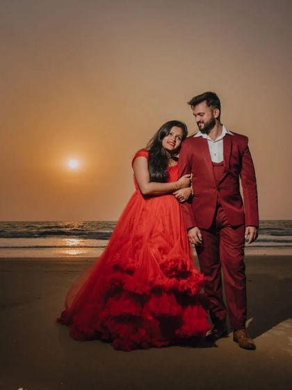 An intimate and romantic beach portrait at sunset. The couple's matching red outfits create a cohesive and visually striking image.