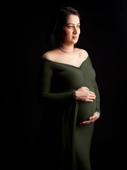 Using dramatic side lighting, this portrait in a fitted green gown creates a powerful sense of mood and mystery. The play of light and shadow beautifully defines the baby bump.