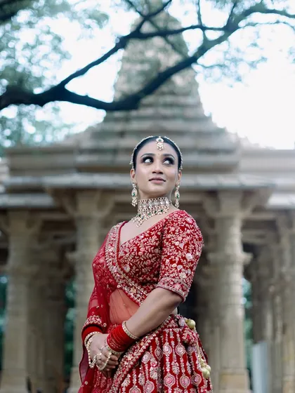 A wide shot that captures the grandeur of the bridal look against a beautiful temple backdrop. The makeup stands out, yet feels harmonious with the entire setting.