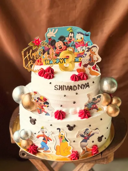 A fun-filled two-tier Mickey Mouse and friends themed cake for a 3rd birthday. All the characters are edible toppers on a chocolate truffle cake.