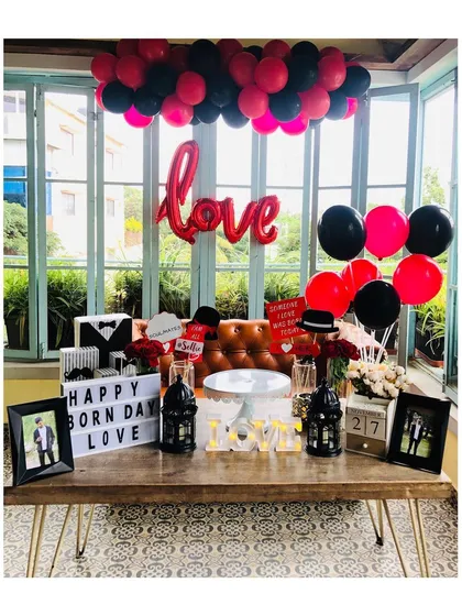 A bold and romantic birthday setup featuring a striking red and black theme. We used a 'love' foil balloon, personalized light-up signs, and themed props to create a fun and stylish atmosphere for the celebration.