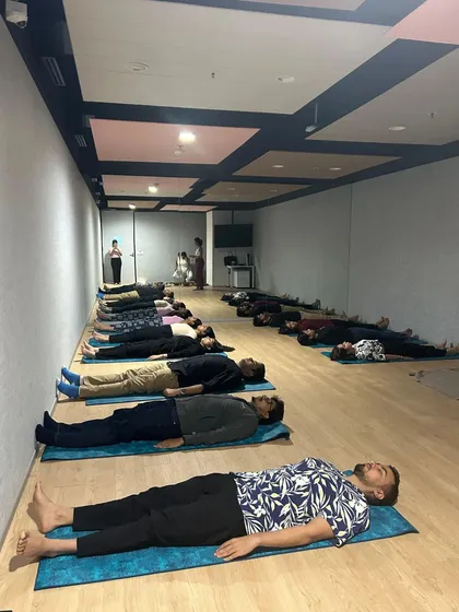 The result of a guided session: employees in a state of complete relaxation. This practice of Savasana, or corpse pose, is essential for integrating the benefits of yoga and meditation, helping to reduce workplace stress and rejuvenate the mind.