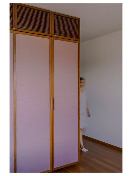 Wardrobe shutters with pink fabric panels and louvered details above, adding a soft, custom touch to a bedroom.