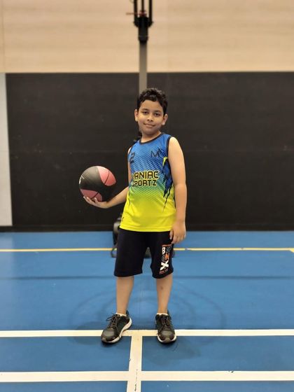 A new player smiles for the camera, holding his basketball and wearing his official academy jersey. Welcome to the team!