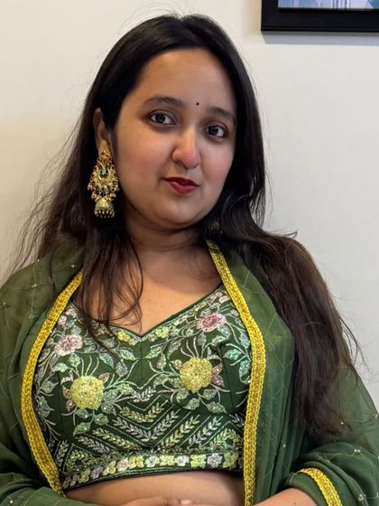 A detailed look at the green embroidered blouse, paired with traditional jhumka earrings. The craftsmanship is evident in the intricate threadwork.