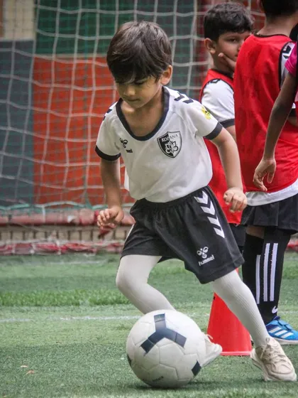 A player demonstrates excellent close control, keeping the ball shielded as he moves through a crowded area during a drill.