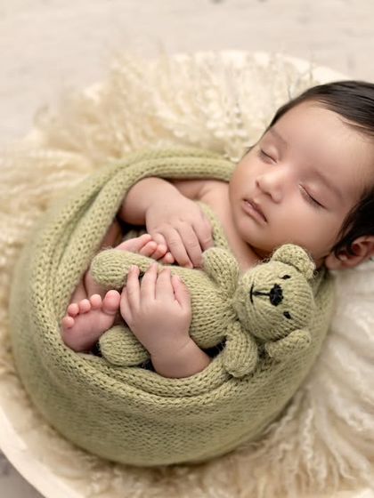 A sweet little teddy bear, wrapped in a green knit blanket and holding a matching toy. The details make these shots so special.