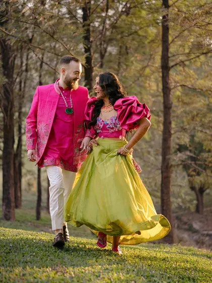 A candid moment of laughter as they walk through a wooded area. The vibrant colors of their outfits pop against the natural greenery, creating a joyful and lively image.
