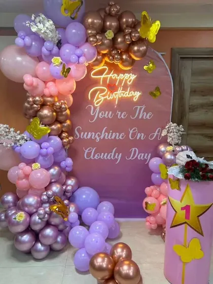 Another view of the personalized first birthday backdrop, showing the mix of pink, purple, and rose gold balloons.