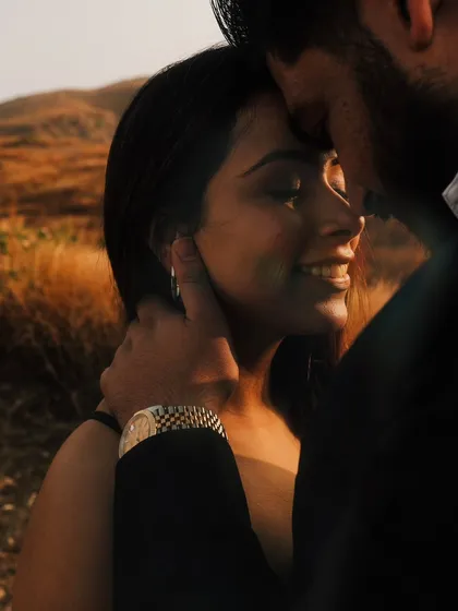 An intimate close-up illuminated by the soft golden hour light. This shot focuses on the tender connection and gentle touch between the couple.
