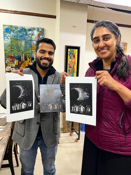 Two participants proudly holding their finished linocut prints from our workshop. The black and white contrast creates a powerful visual impact.