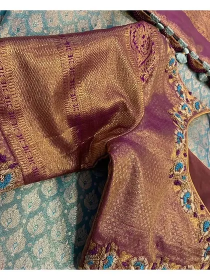 A close-up of a violet brocade sleeve, showing how the traditional woven border is enhanced with custom floral embroidery in turquoise and gold.