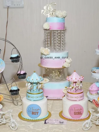 A complete and beautiful dessert table setup for a baby shower, featuring a tiered cake, carousel cakes, cupcakes, and more.