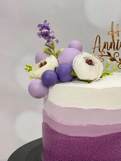 A close-up of the purple ombre anniversary cake, highlighting the textured frosting and the beautiful floral arrangement.