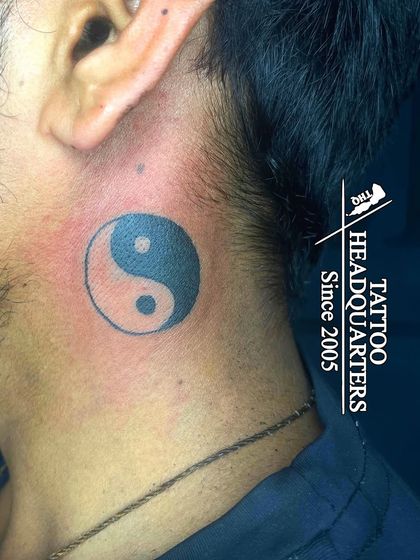 A bold Yin and Yang symbol tattooed on the neck, representing the concept of dualism and balance in all things.