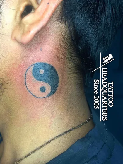 A bold Yin and Yang symbol tattooed on the neck, representing the concept of dualism and balance in all things.