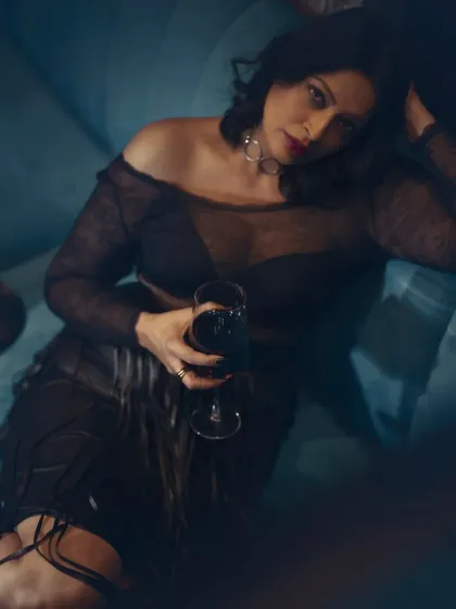 A moody and introspective shot. This all-black look with a sheer top and fringed skirt is about expressing a bold, unapologetic attitude through fashion.