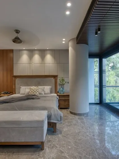 Another angle of the East Punjabi Bagh bedroom, highlighting the floor-to-ceiling windows that flood the space with natural light and offer a view of the green outdoors.