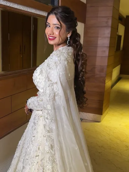 A side profile showcasing the elegant messy ponytail and the radiant makeup. The red lip adds a perfect touch of drama to this beautiful sangeet look.