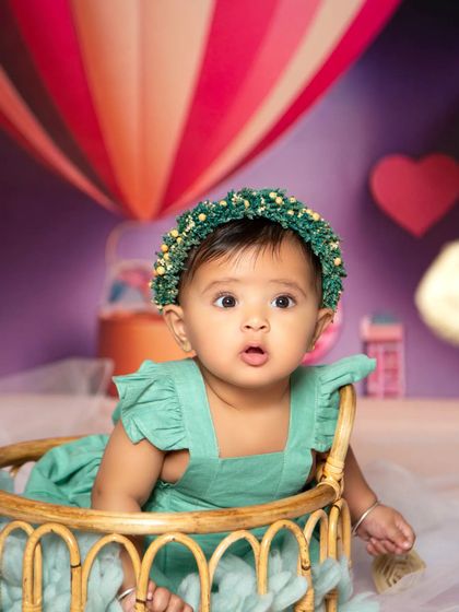 A sweet close-up from the hot air balloon adventure, showing the baby's adorable expression and green floral crown.