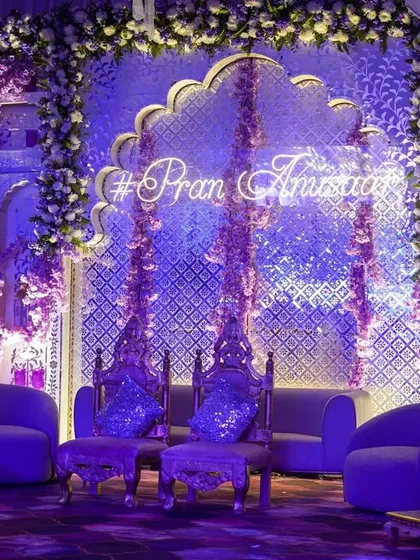 A closer view of the lavender-lit engagement stage. The ornate silver chairs for the couple are set against the glowing neon hashtag and the intricate backdrop, creating a picture of royal elegance.