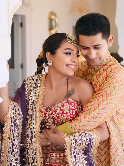 An adorable, happy portrait of Mishi and her groom. Her fun bubble braid and glowing makeup reflect her personality and the joyful energy of their Mehndi event.