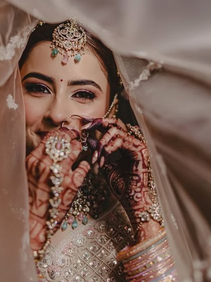 A lovely shot of a bride, with her beautifully stained hands peeking through her veil. The dark henna adds a layer of traditional beauty to her look.
