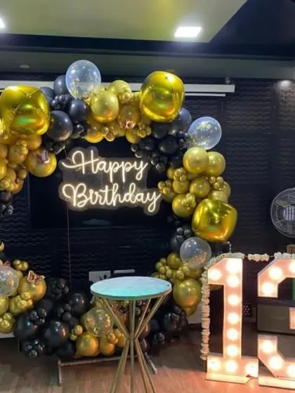A cool and stylish black and gold theme for a 13th birthday. The full balloon ring, neon sign, and light-up numbers create the perfect trendy backdrop for a teenager's party.