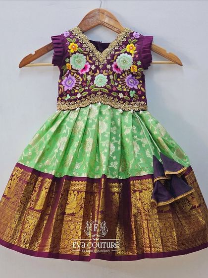 A beautiful Kanchi Pattu lehenga for a little one, featuring a light green skirt with a purple zari border and a heavily embroidered purple blouse.