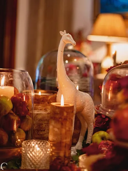 Another view of the giraffe figurine amidst the candlelight and glass cloches. This highlights how I layer different decorative elements to build a rich and complex visual story on the table.
