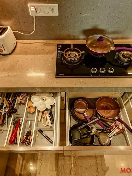 Organized drawers in a C-shaped acrylic kitchen, with compartments for cutlery and utensils.