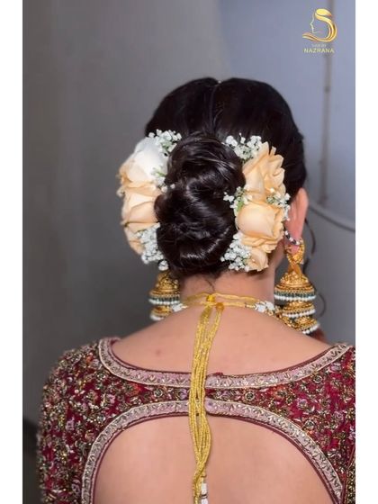 A close-up of a textured bridal bun adorned with soft peach roses and baby's breath.