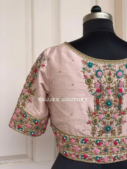 The back of the light pink peacock blouse. The embroidery is centered on the back, creating a beautiful focal point with two peacocks surrounded by floral patterns.